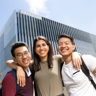 Smiling students standing in front of building