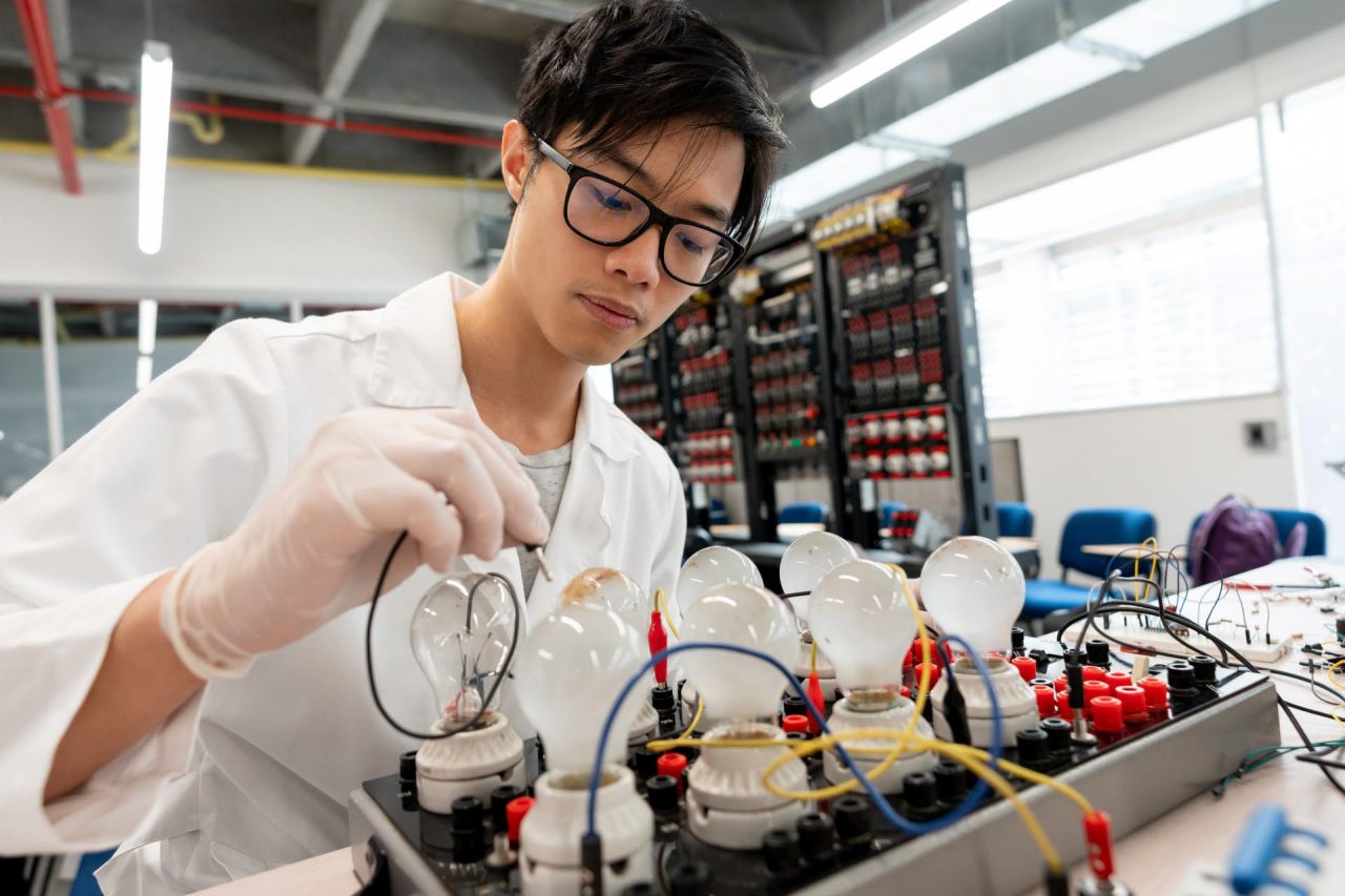 Asian student at electronics laboratory experimenting looking focused